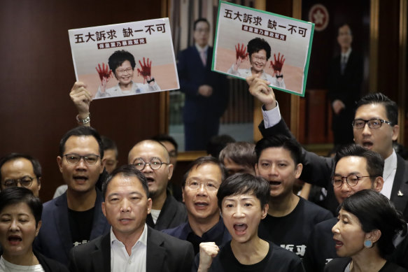 Pro-democracy legislators wave placards showing Carrie Lam with blood on her hands.