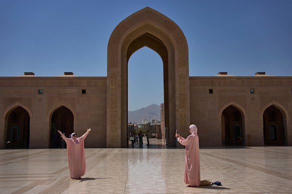Tourists take photos at the Sultan Qaboos Grand Mosque in Muscat, Oman.