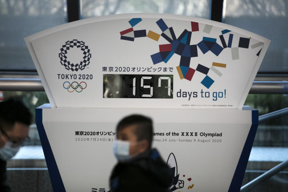 Coronavirus fears: People wear face masks in Tokyo as the countdown clock to the Olympic Games ticks down.