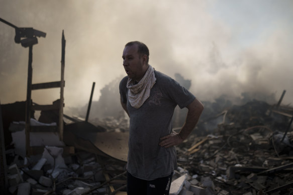 A neighbour pauses as he tries to extinguish the fire of a house, destroyed after a Russian attack in Kharkiv.