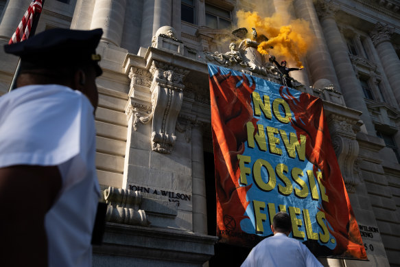 A demonstrator scales the John A. Wilson Building in Washington, DC, in April 2022 to mark Earth Day.