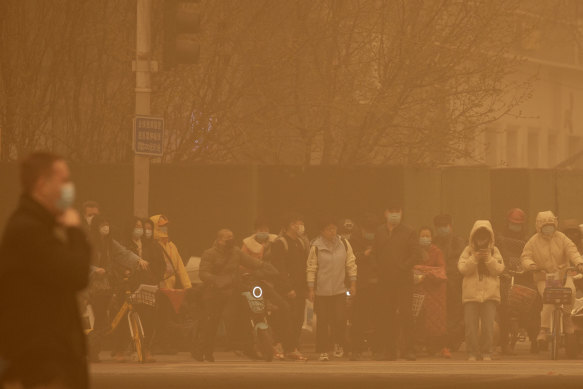 People wait to cross an intersection in Beijing during Monday’s sandstorm.