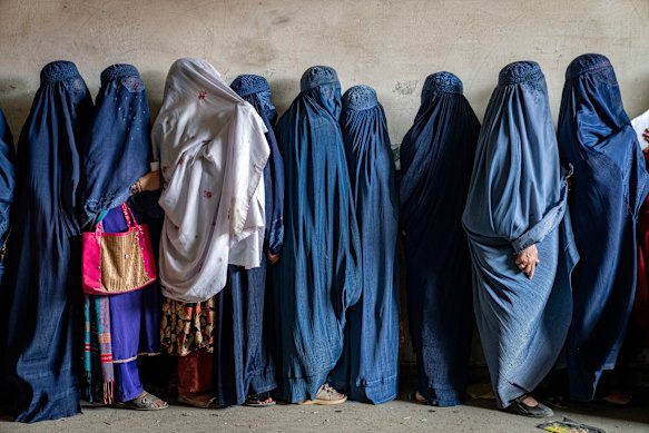 Afghan women wait to receive food rations distributed by a humanitarian aid group, in Kabul.