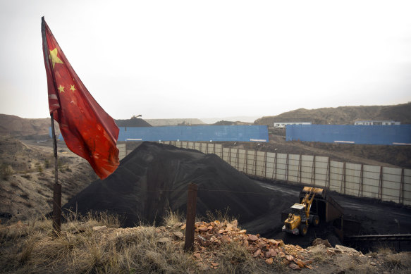 A Chinese flag stands in the breeze as a loader moves coal at a coal mine in Inner Mongolia.