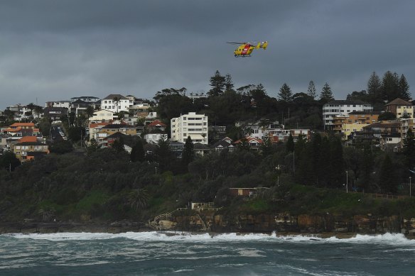 A helicopter searches along the coastline for a surfer who went missing at Coogee Beach yesterday. 