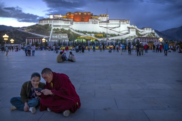A monk and a woman stare at their smartphones in the square in front of the Potala Palace in Lhasa, Tibet. It was seen last year when the government visited foreign journalists.