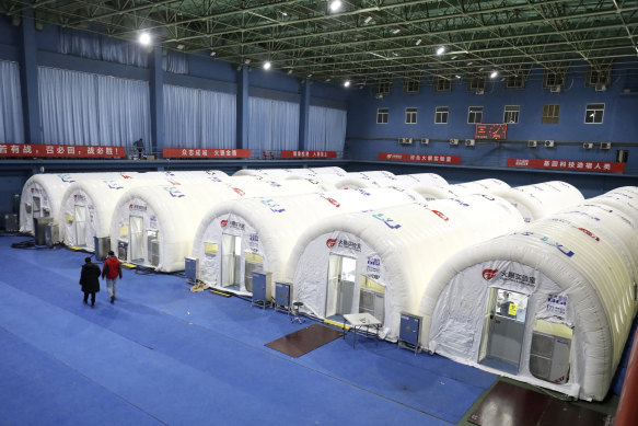 Workers walk past a temporary COVID-19 testing laboratory built on an indoor tennis court in Shijiazhuang in northern China's Hebei Province.