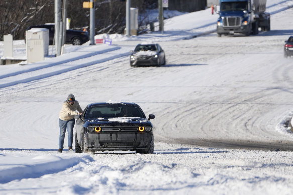 A person attempts to push a car through snow in Nashville, Tennessee, where temperatures reached minus 16 degrees overnight.