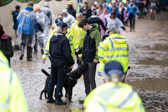 Police officers and a drug detection dog walk among the crowd at the entrance of Splendour in the Grass 2022.