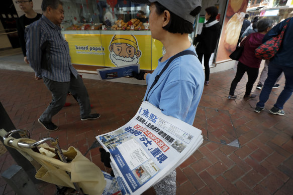 A vendor gives out copies of newspaper with a headline about the coronavirus in Hong Kong.