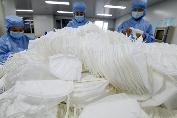 Workers wearing face masks to protect themselves from the coronavirus arrange the face masks at a factory in Handan, Hebei province, China, in January.