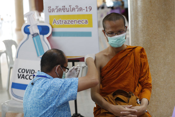 A Thai health worker administers a dose of the AstraZeneca COVID-19 vaccine to a Buddhist monk.