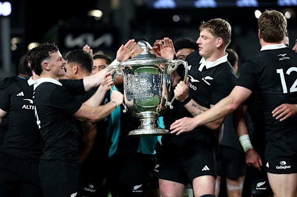 The All Blacks lift the Bledisloe Cup after their victory over the Wallabies.