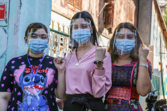 Young women show their inked fingers, a sign they voted in elections in 2020.