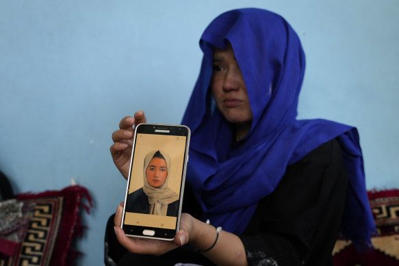 An Afghan girl shows a picture of her 19-year-old sister who was victim of a suicide bomber, in Kabul.