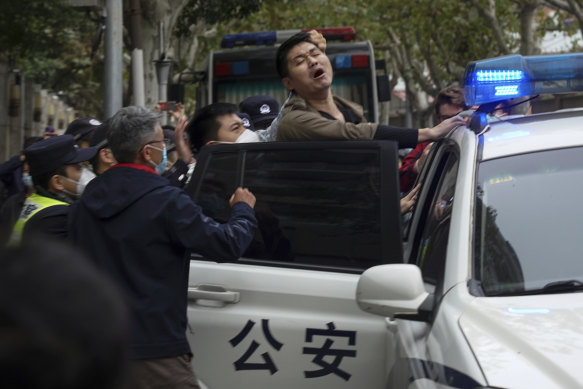 A protester reacts as he is arrested by policemen during a protest on a street in Shanghai, China.