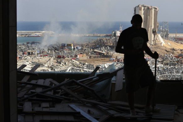 A man stands in a damaged apartment as he looks out at the scene of a massive explosion.