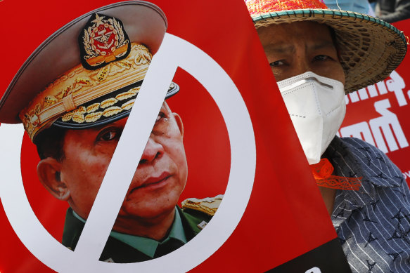 A protester holds a placard with the face of Myanmar’s commander in chief, Senior General Min Aung Hlaing during an anti-coup rally in front of the Myanmar Economic Bank in Mandalay.