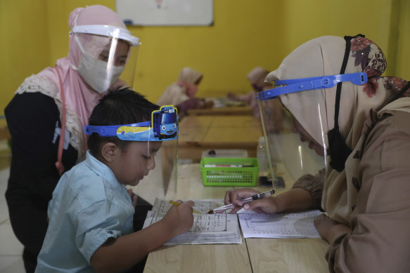Teachers and students wear protective gear at a Koran educational facility at on the outskirts of Jakarta.