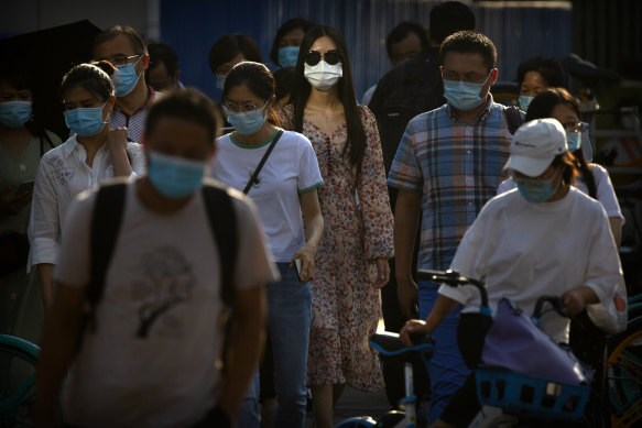 People wearing face masks wait to cross an intersection in the CBD in Beijing.