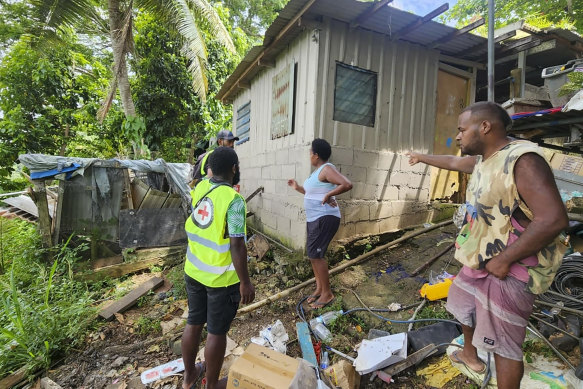 Red Cross volunteers assist locals as they inspect their damaged house in Efate, Vanuatu.