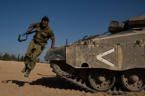 An Israeli soldier jumps off the front of a tank in southern Israel.