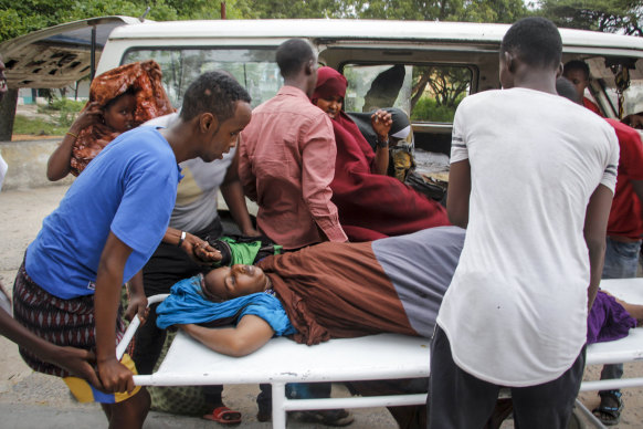Medical workers and other Somalis help a woman, who was wounded when a powerful car bomb blew off the security gates to the Elite Hotel, as she arrives at a hospital in Mogadishu.