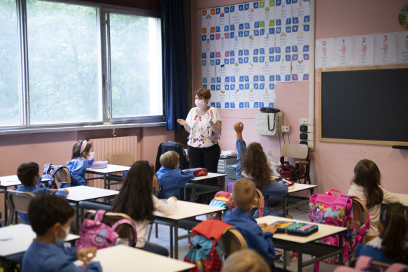 Children and their teacher wear protective masks inside an elementary school