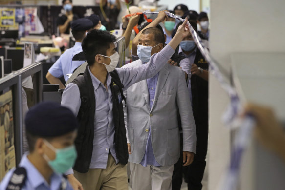Jimmy Lai is escorted by police inside the Apple Daily newspaper headquarters. 