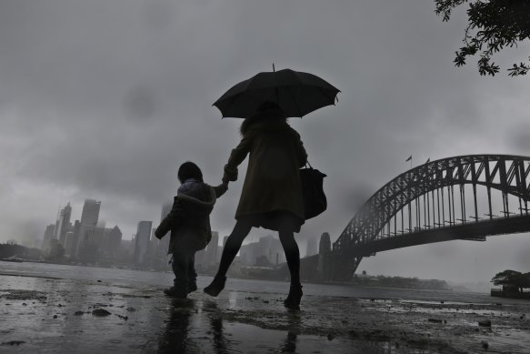 A woman and child walk through Kirribilli as the rain hit Sydney again on Thursday.