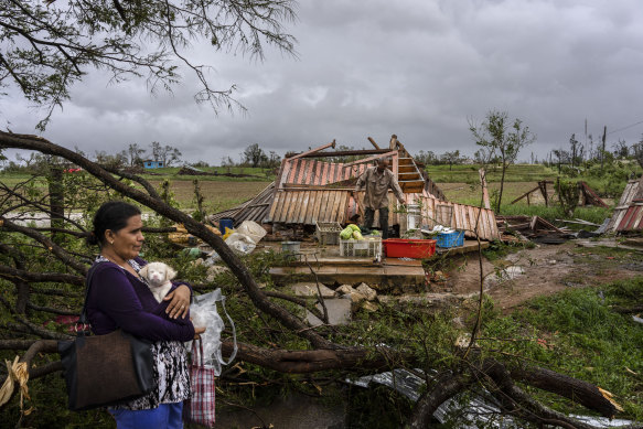 Mercedes Valdez holds her dog Kira as she waits for transportation after losing her home to Hurricane Ian in Pinar del Rio, Cuba.