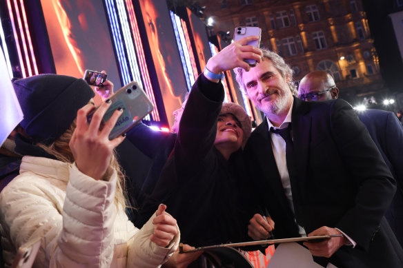 Joaquin Phoenix takes pictures with fans at the UK premiere of Napoleon. 