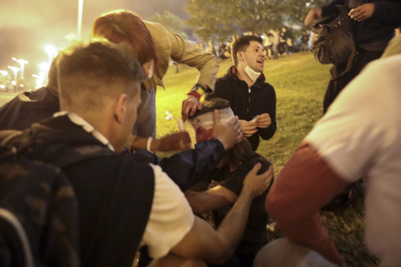 Protesters provide first aid to a wounded man during clashes with police after the presidential election in Minsk early on Monday.