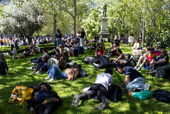 People lie on the grass near Madrid Puerta de Atocha –  Almudena Grandes train station – while the station is closed.