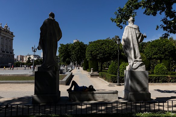 A woman takes rest under the shade of a tree at Plaza de Oriente in Madrid.