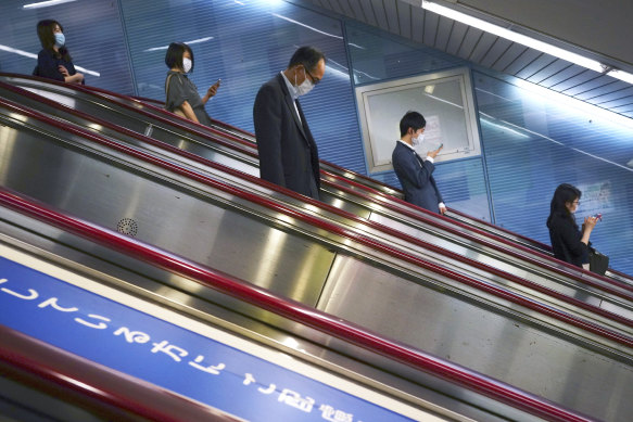 People using escalators in Tokyo, where restrictions are not lifted. 