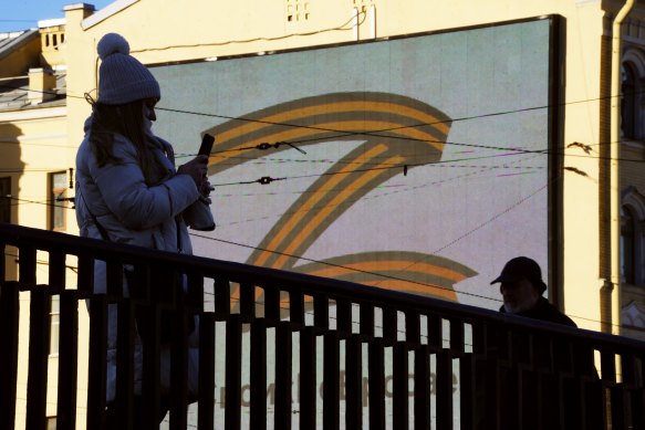 People walk past the letter Z, which has become a symbol of the Russian military, on an advertisement screen in St Petersburg, Russia.