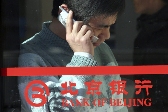 A man uses his mobile phone near the Bank of Beijing logo.  The former head of the state-owned bank is under investigation for corruption.