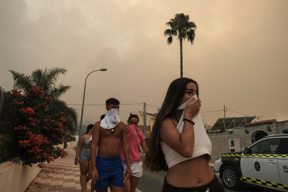 Residents protect themselves from the smoke as a wildfire advances near a residential area in Alhaurin de la Torre, Malaga, Spain.