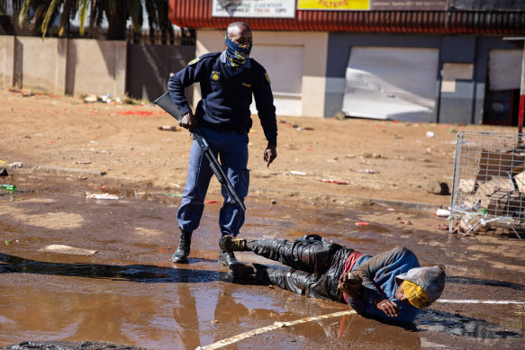 South African police force suspected looters to lie down and roll in muddy water after apprehending them in Soweto, Johannesburg. 