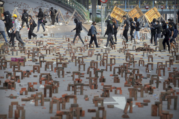 Protesters walk past barricades of bricks on a road near the Hong Kong Polytechnic University in Hong Kong.