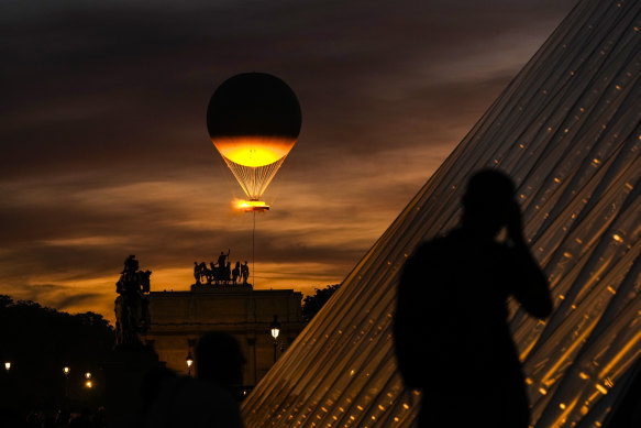 The Olympic cauldron and its balloon, suspended above the Paris sky.