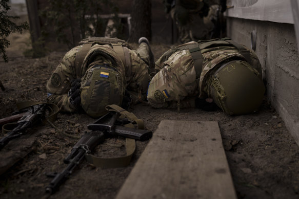 Ukrainian soldiers take cover from incoming artillery fire in Irpin on Sunday.