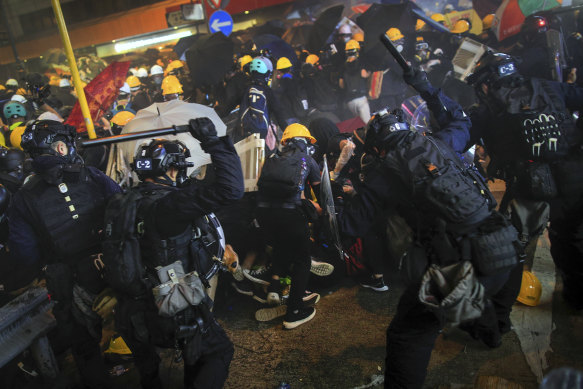 Police with batons charge protesters.