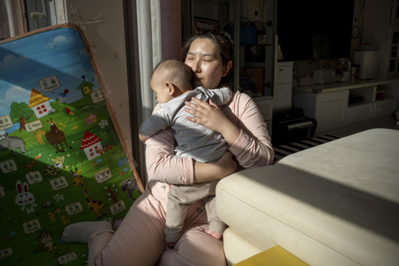 Su Yue and her son play on the balcony of their house in Beijing.