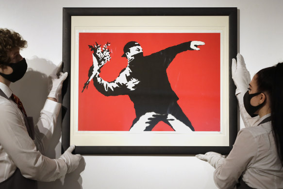 Gallery technicians display a Banksy called Love is in the Air.