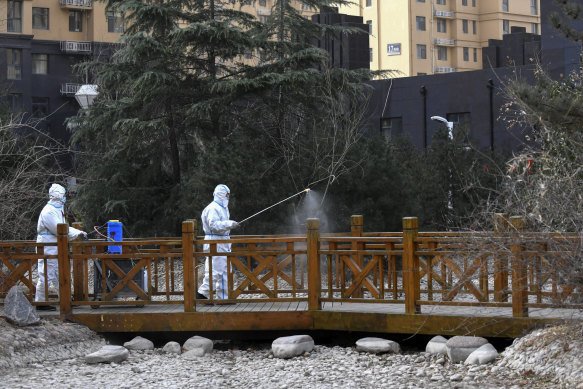 Workers in protective suits spray disinfectant near a residential area in Shijiazhuang.