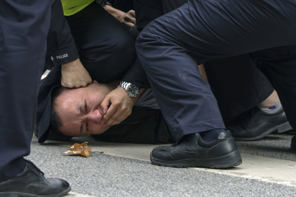 Police pin down a protester on a street in Shanghai on Sunday.