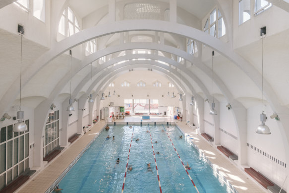 People swim beneath the vaulted ceiling of the Butte-aux-Cailles municipal pool in Paris.