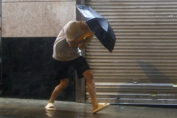 A man with an umbrella struggles against strong wind and rain brought by super typhoon Saola in Hong Kong.